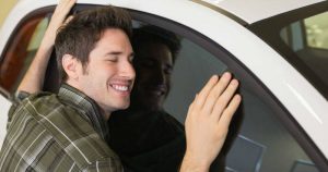 Joven abrazando su auto nuevo.