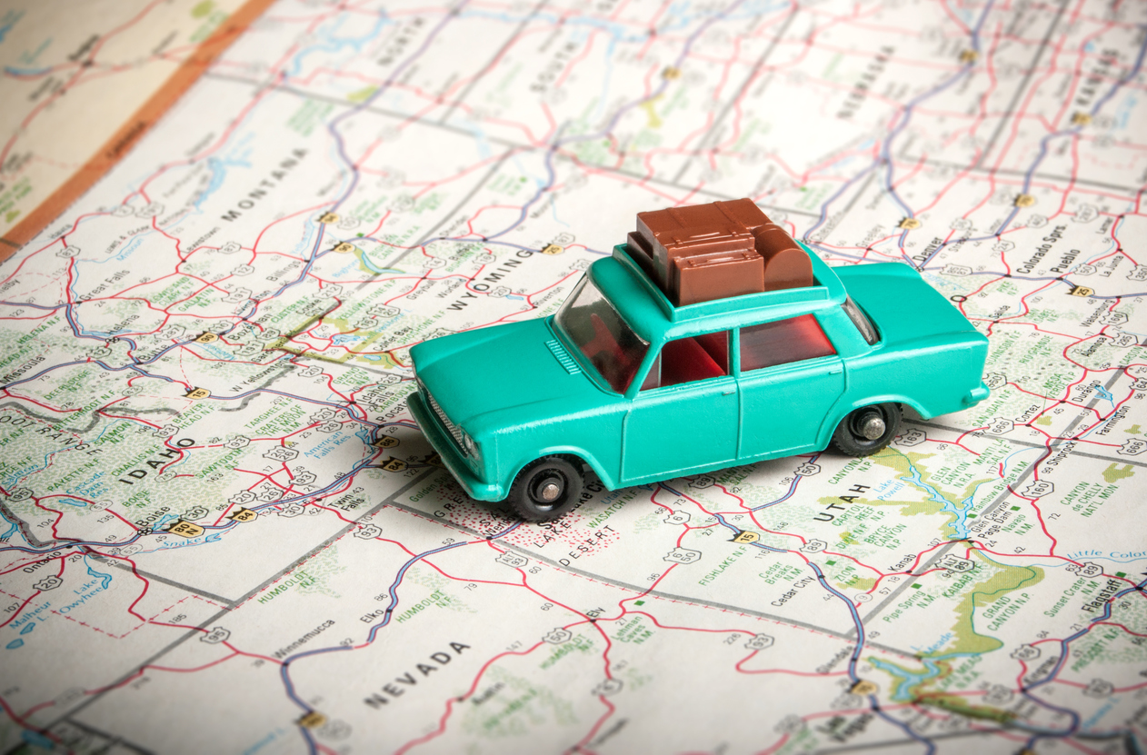 Auto a escala color verde sobre un mapa de rutas de viaje.
